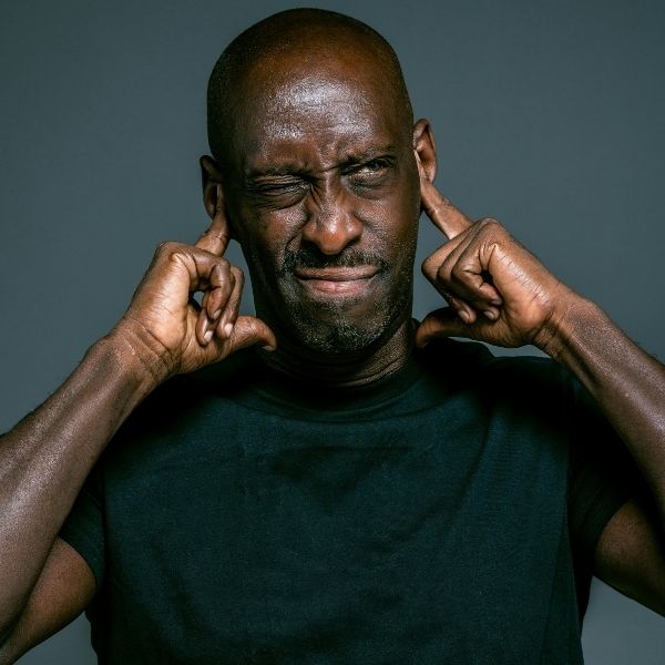 man holding his ears due to a loud sound